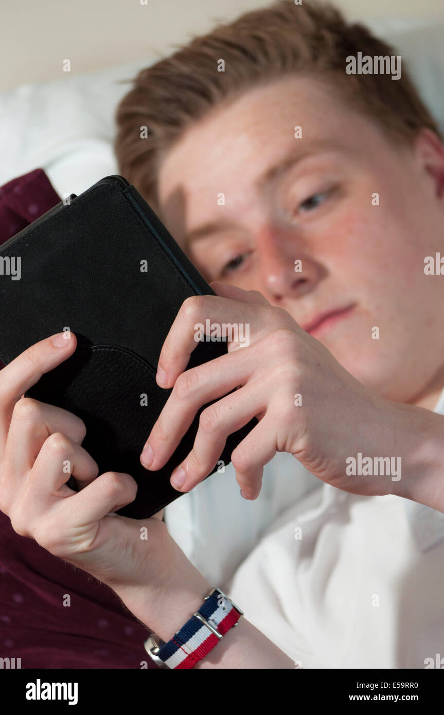 La juventud masculina joven leer e reader kindle absorto en la novela libro Foto de stock