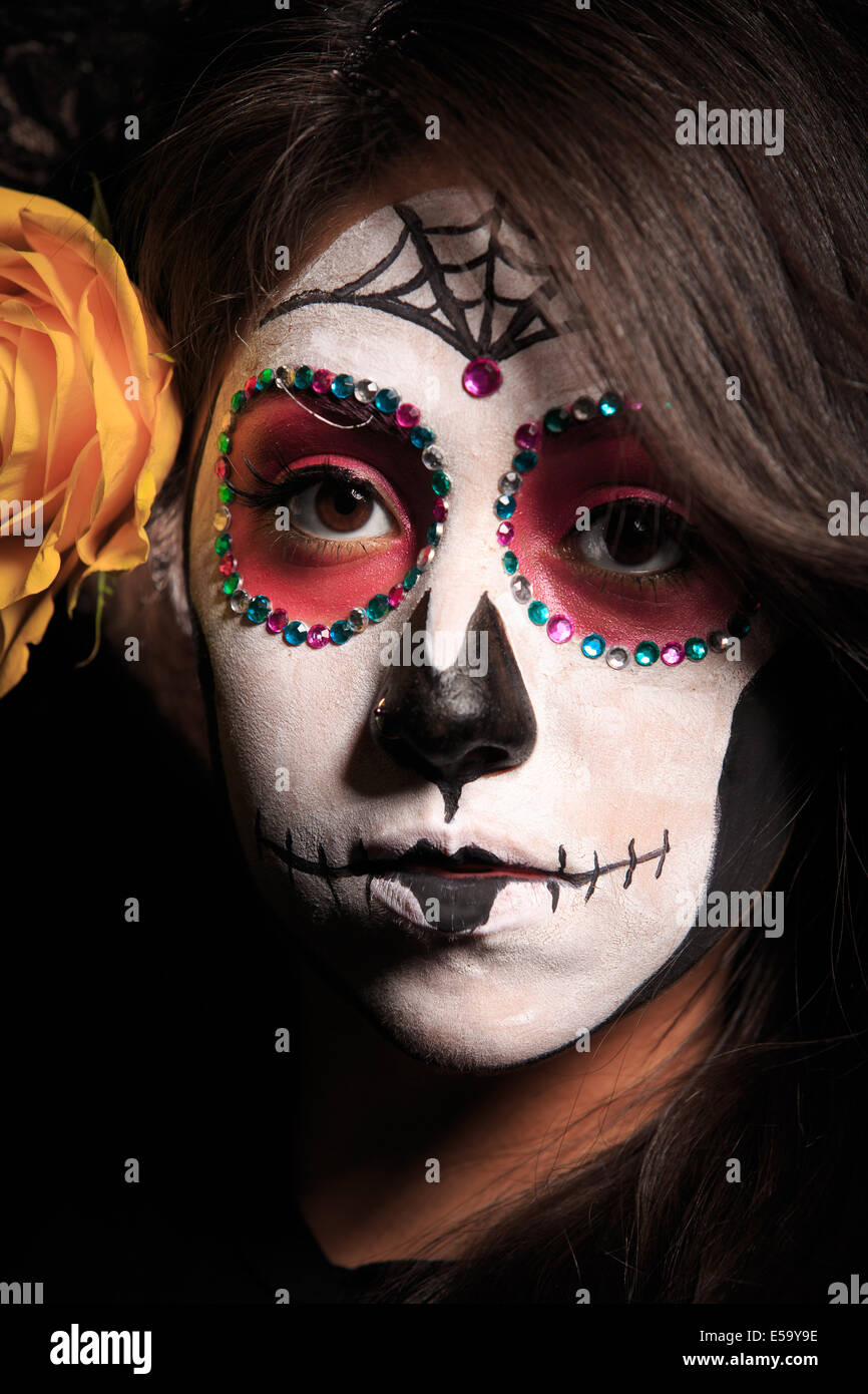 Una mujer joven con pintura facial en forma de calaveras de azúcar  decoradas para el Dia de los Muertos Fotografía de stock - Alamy