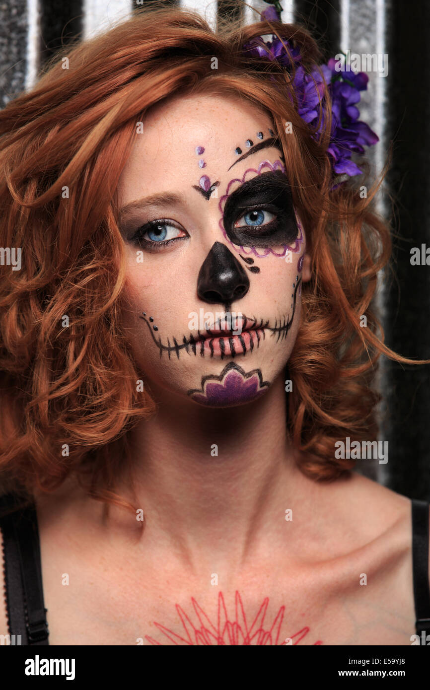 Una mujer joven con pintura facial en forma de calaveras de azúcar  decoradas para el Dia de los Muertos Fotografía de stock - Alamy