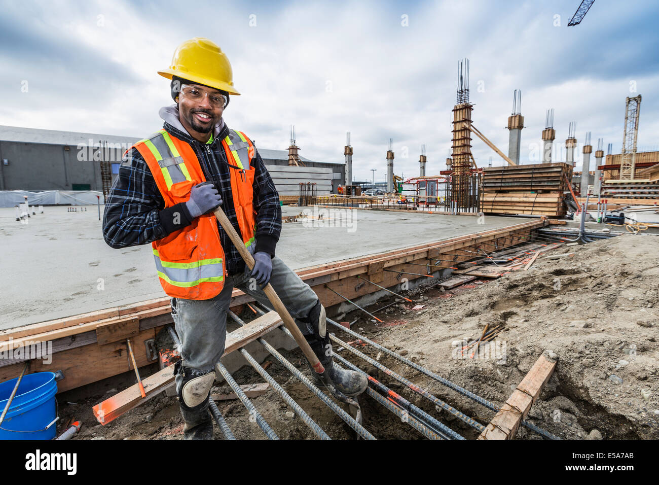 Trabajador negro sonriente en sitio en construcción Foto de stock