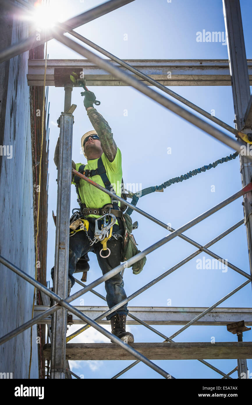 Trabajador caucásico en andamios en sitio en construcción Foto de stock