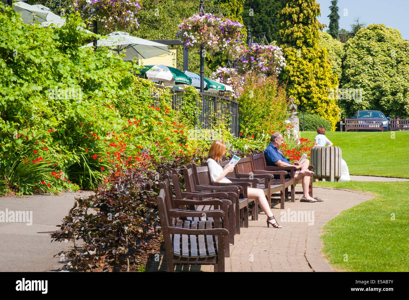 El noroeste de Londres, Golders Hill Park, bancos hierba restaurante Cafe árboles flores hombre mujer mujeres sombrillas sombrillas verano Foto de stock