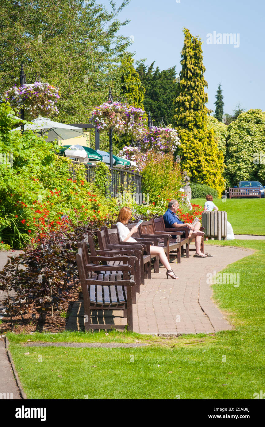 El noroeste de Londres, Golders Hill Park, bancos hierba restaurante Cafe árboles flores hombre mujer mujeres sombrillas sombrillas verano Foto de stock