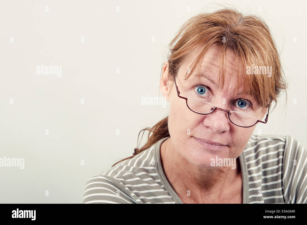 Retrato de una mujer con gafas de lectura mirando a la cámara. Foto de stock