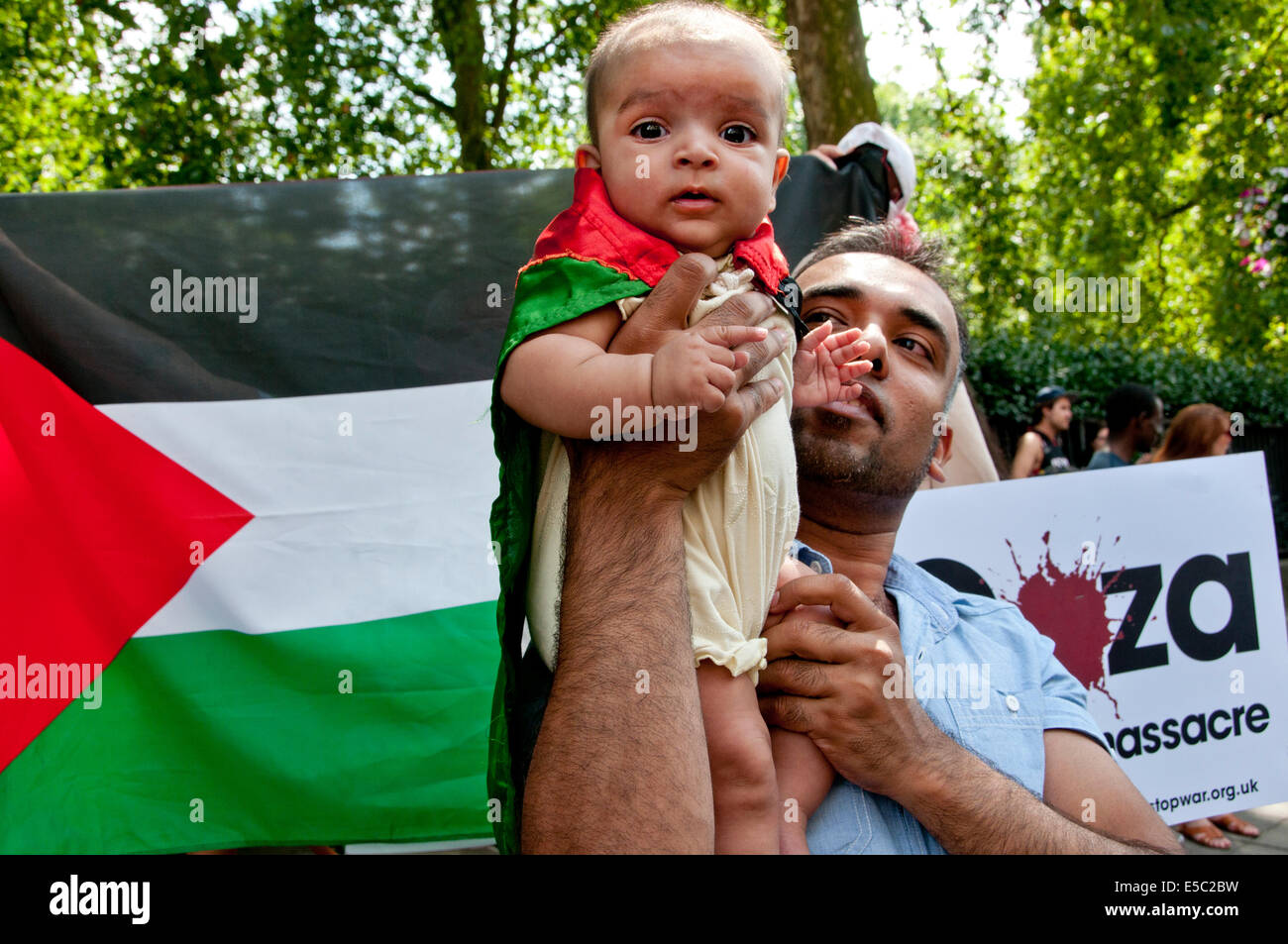 Manifestación contra el bombardeo israelí de Gaza, 26.07.2014. Un joven niño envuelto en una bandera palestina es sostenido por su padre. Foto de stock