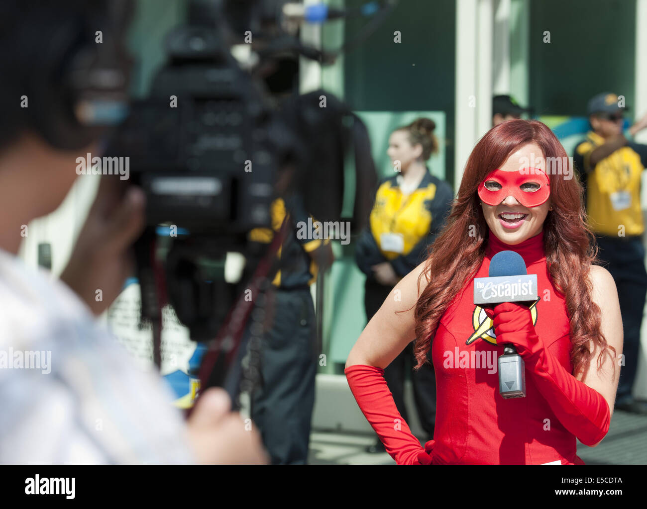 San Diego, California, USA. 26 de julio de 2014. Una joven y hermosa mujer  vestida de rojo de anclaje tipo Shazam traje con máscara informes sobre  cámara con micrófono delante del Centro