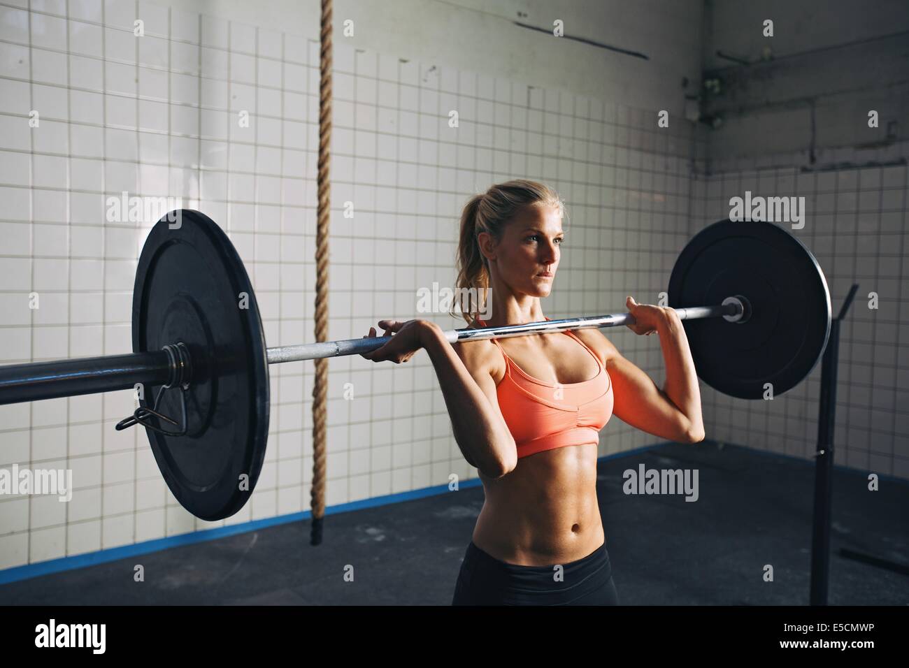 Mujer Fitness concentrando mientras barras de elevación. Mujer fuerte crossfit levantamiento de pesas en el gimnasio. Caucásica modelo femenino con mu Foto de stock