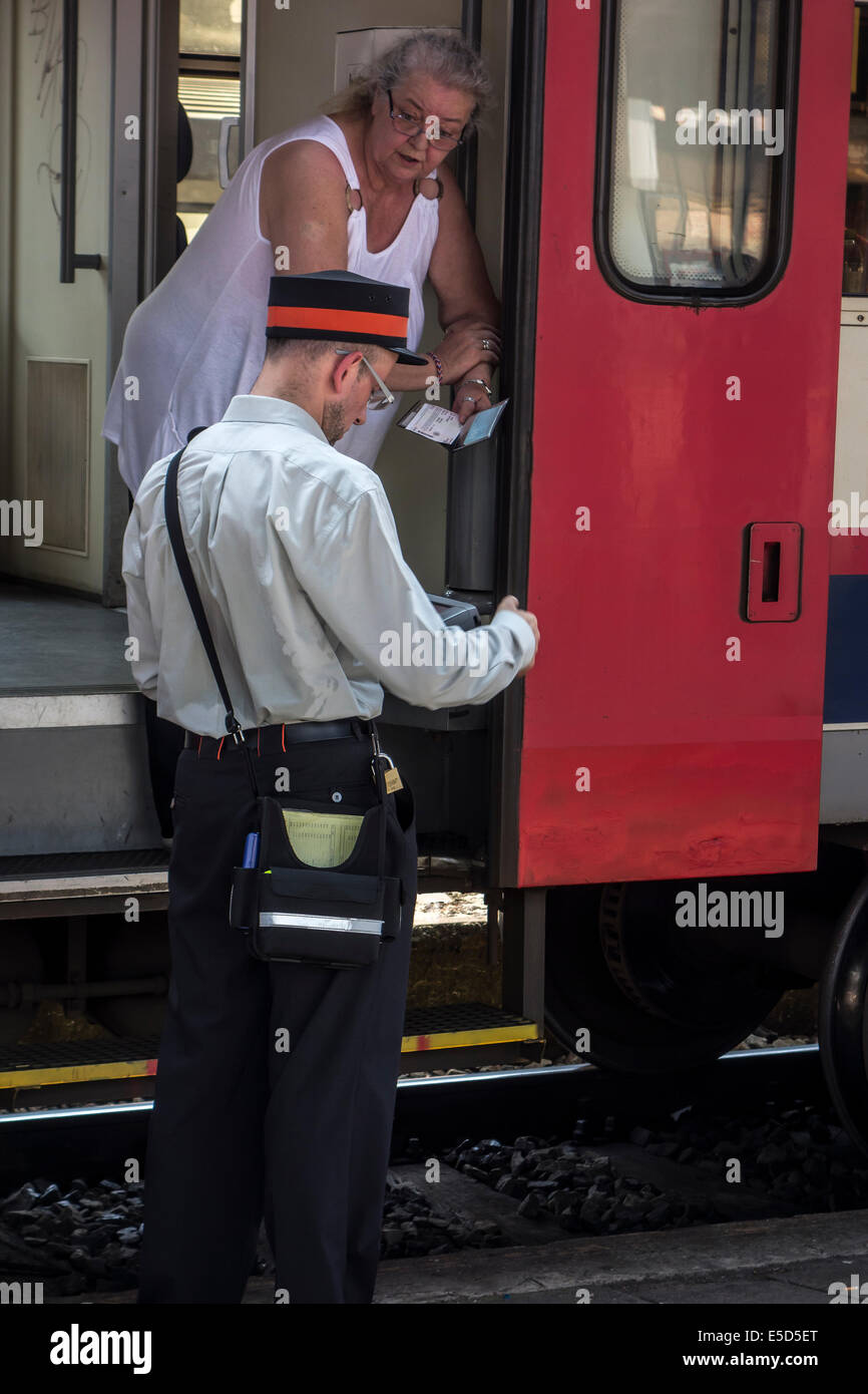 Ancianos pasajera pidiendo información al empleado ferroviario / inspector de billetes de tren en la plataforma en la estación de ferrocarril Foto de stock