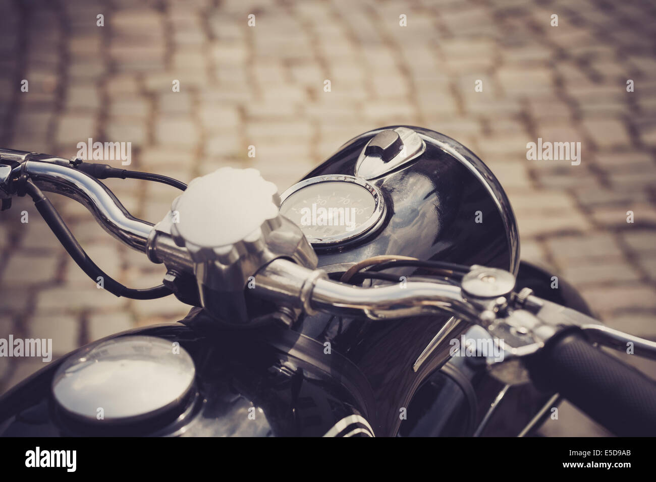 Una motocicleta vintage con una carretera adoquinada en el fondo Foto de stock