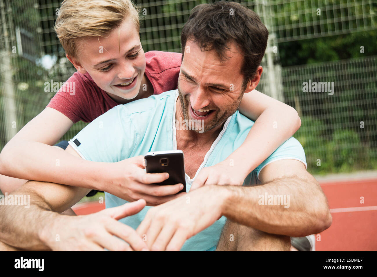 Alemania, Mannheim, padre e hijo mirando al teléfono inteligente. Foto de stock