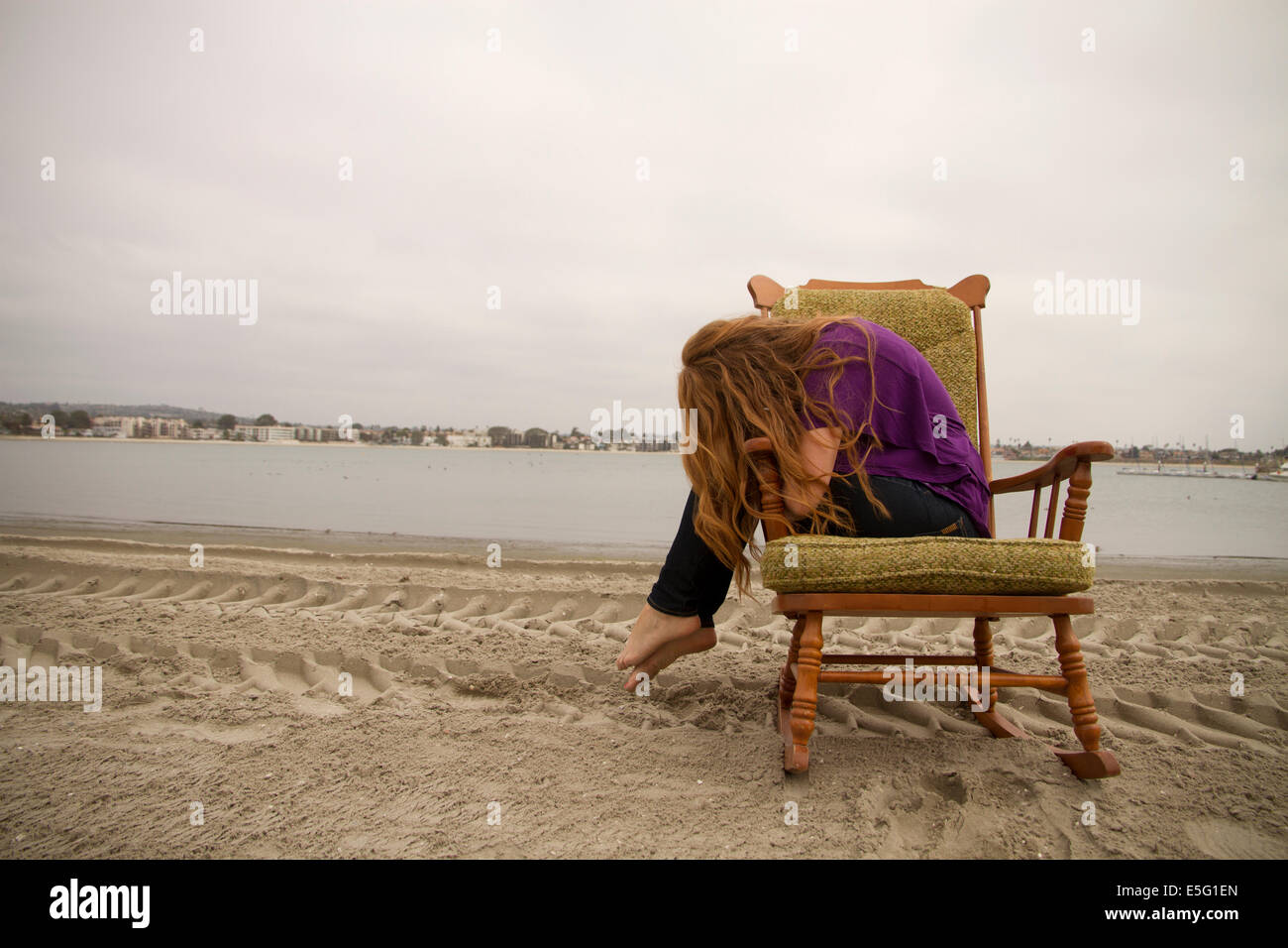 Retrato de mujer joven sentado en una silla en la playa Foto de stock