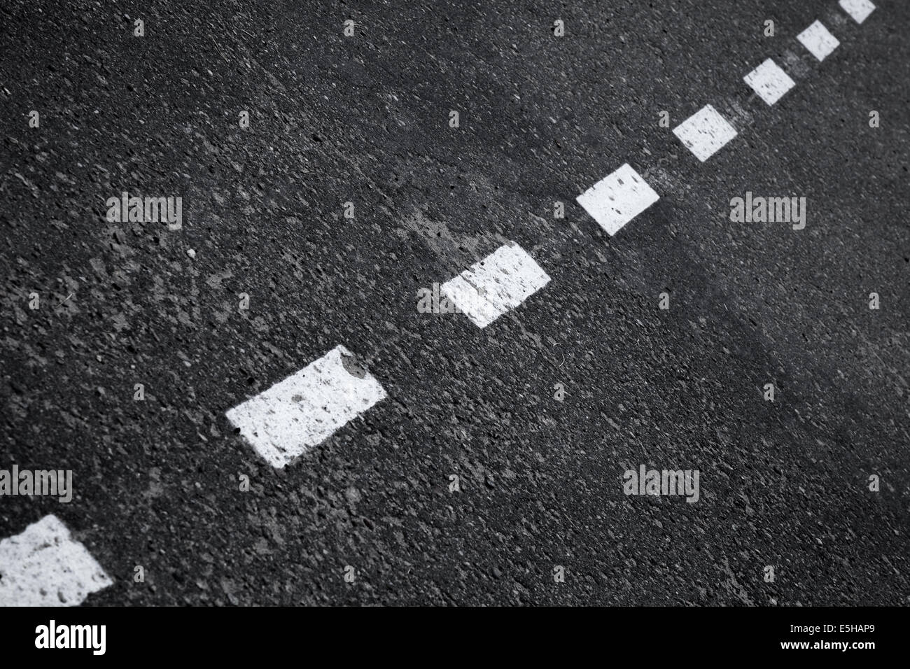Antecedentes El asfalto oscuro con rayas marcando la línea divisoria Foto de stock
