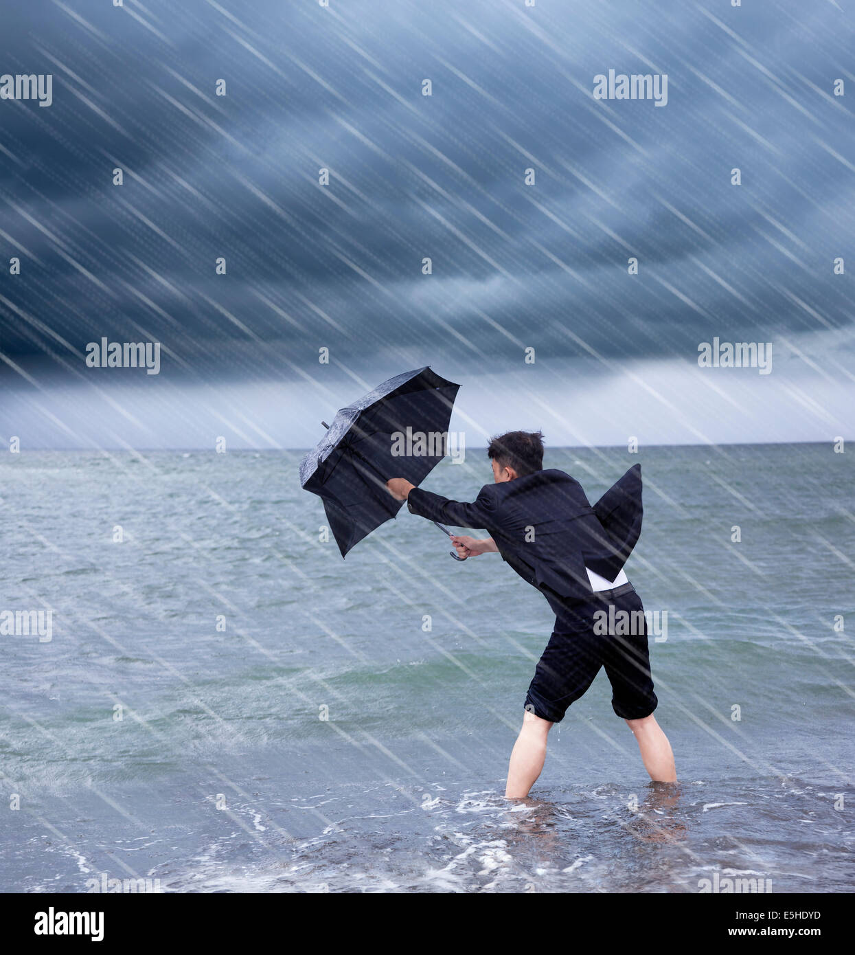 Hombre de negocios sosteniendo un paraguas para resistir la tormenta Foto de stock