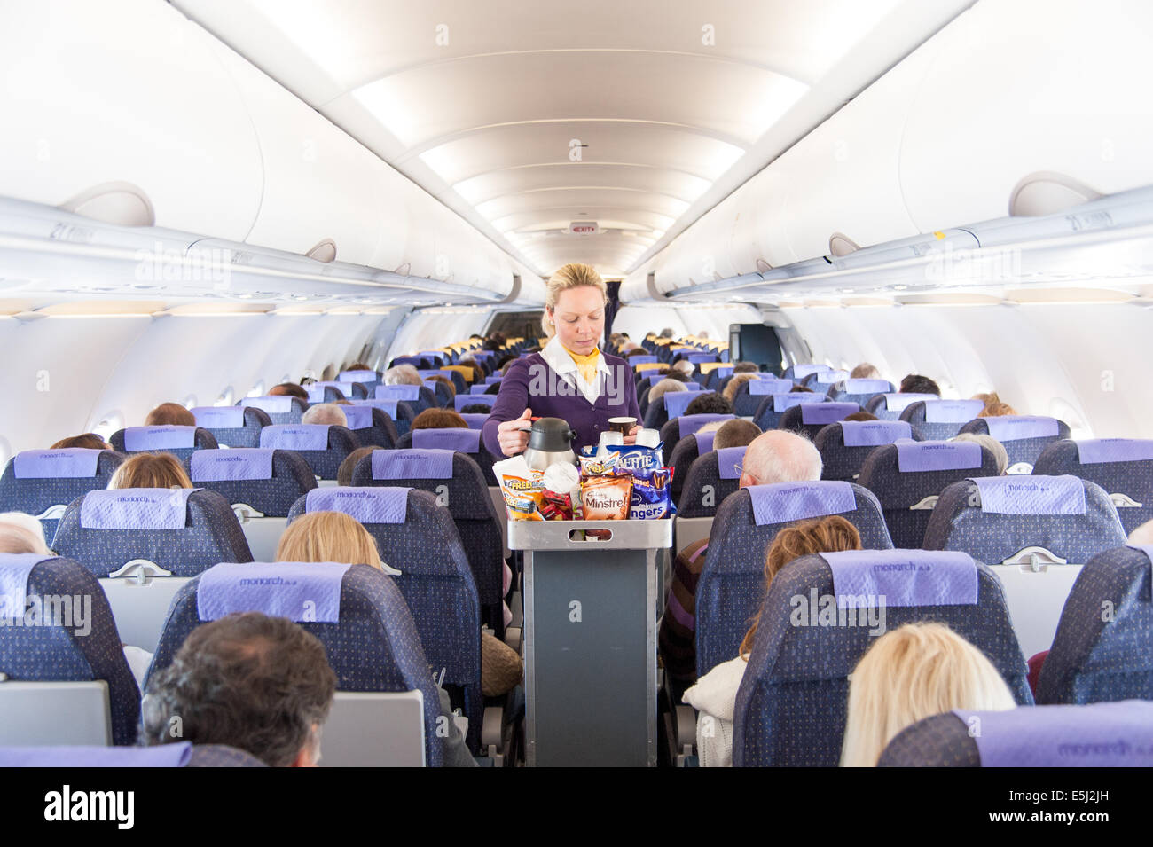 Monarch Airlines, azafata aérea que sirve aperitivos del carrito de bebidas, Reino Unido Foto de stock