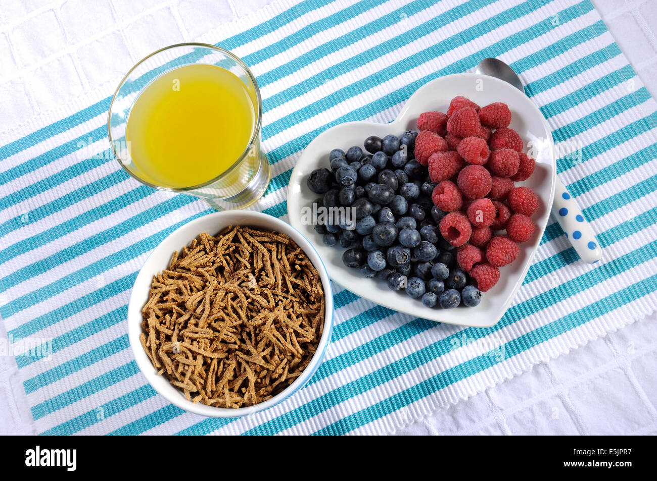 Dieta saludable Una dieta alta en fibra con desayuno tazón de cereal de salvado y bayas de color blanco en la placa del corazón aqua azul con piña Foto de stock
