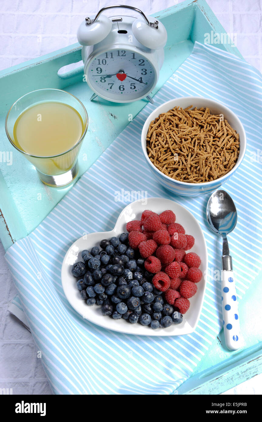 Dieta saludable Una dieta alta en fibra con desayuno tazón de cereal de salvado y bayas de color blanco en la placa del corazón aqua blue bandeja vintage Foto de stock
