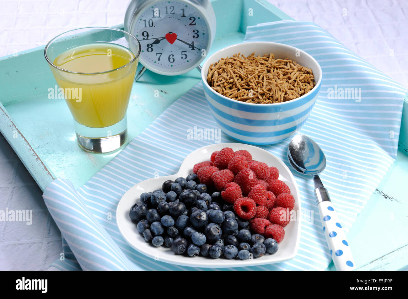 Dieta saludable Una dieta alta en fibra con desayuno tazón de cereal de salvado y bayas de color blanco en la placa del corazón aqua blue bandeja vintage Foto de stock