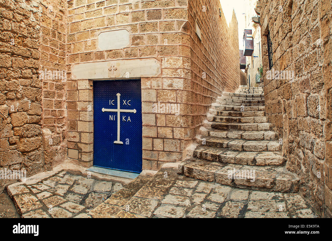Puerta metálica con cruz blanca en la entrada a la pequeña iglesia y sus  estrechas calles empedradas en Jaffa, Israel Fotografía de stock - Alamy