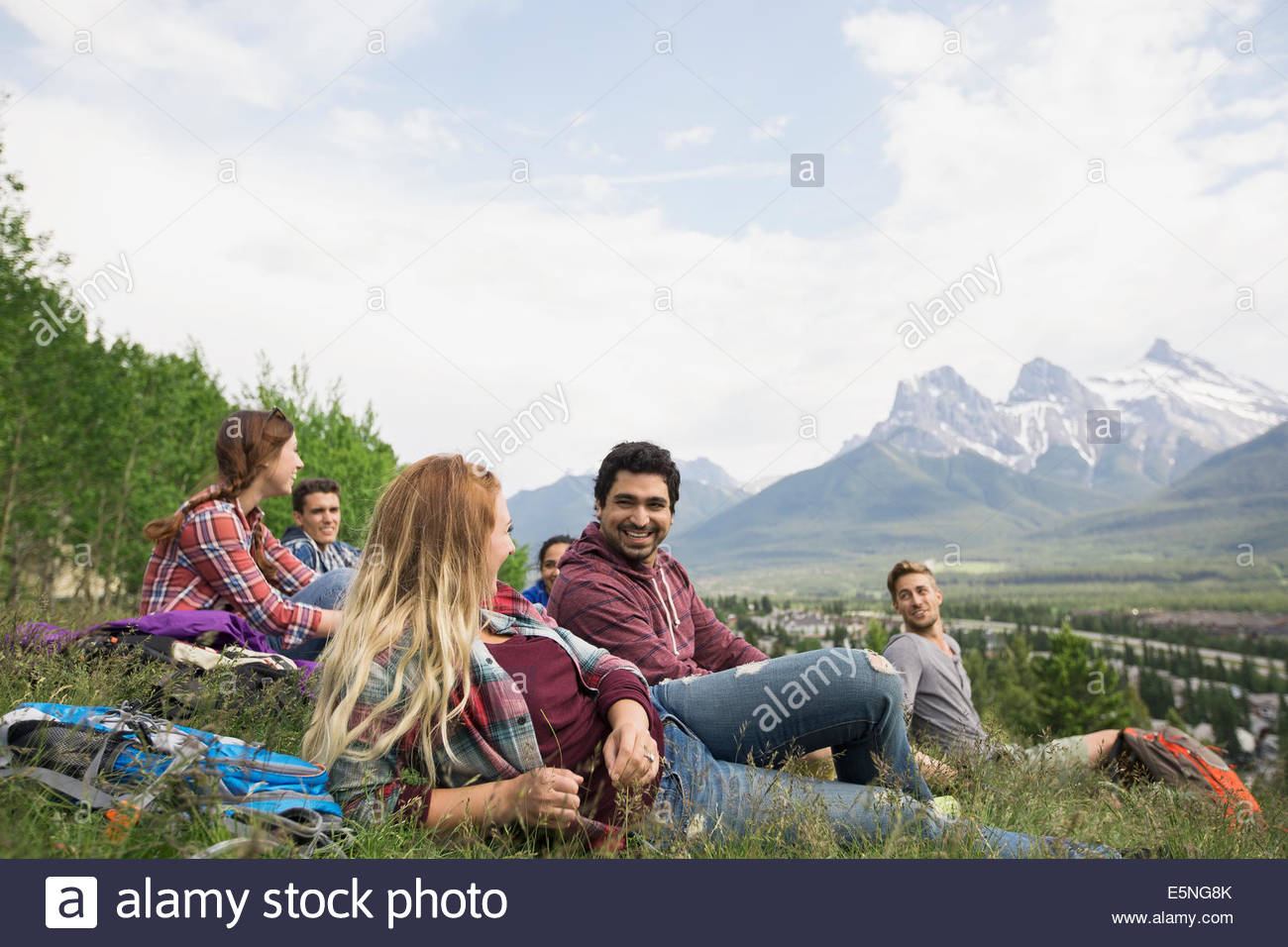 Amigos descansando en la hierba cerca de las montañas Foto de stock