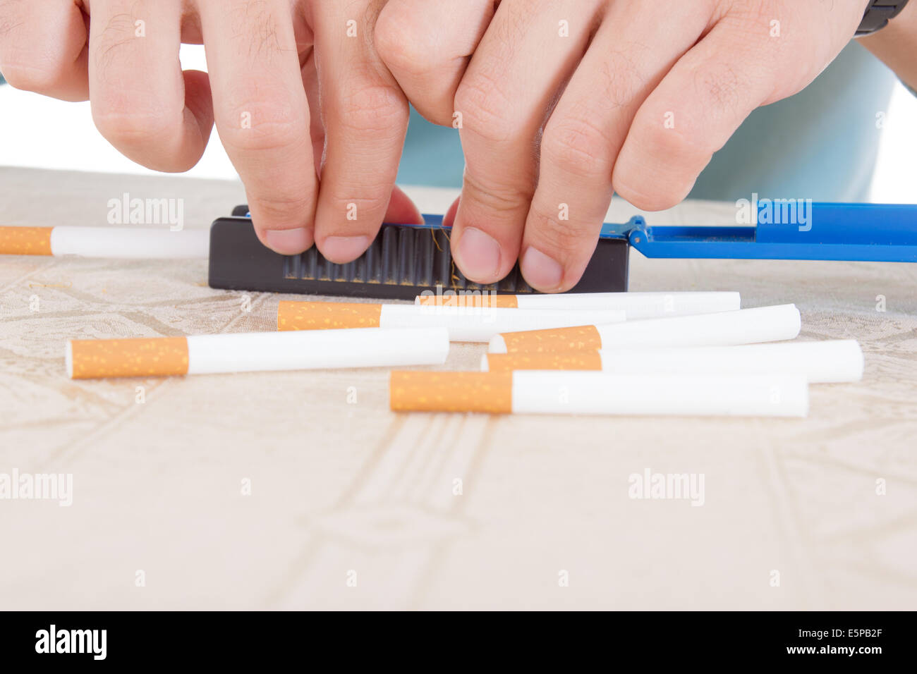 Las manos haciendo puros utilizando rollings y papel adhesivo con dulce de tabaco de fumar Foto de stock