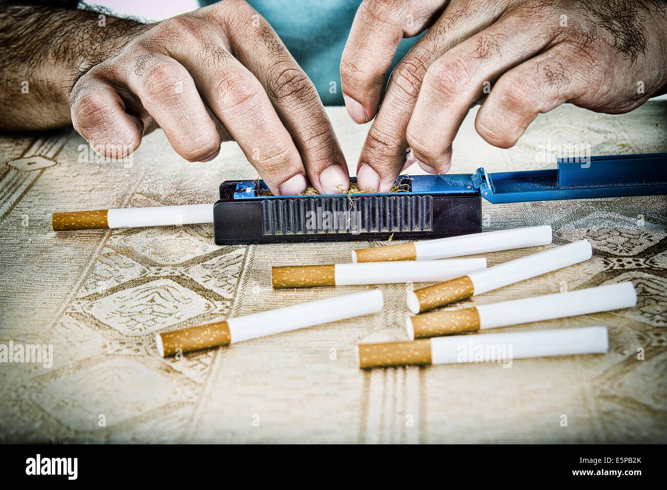 Las manos del hombre preparando para hacer los cigarrillos fuman cigarros con tabaco y filtros Foto de stock