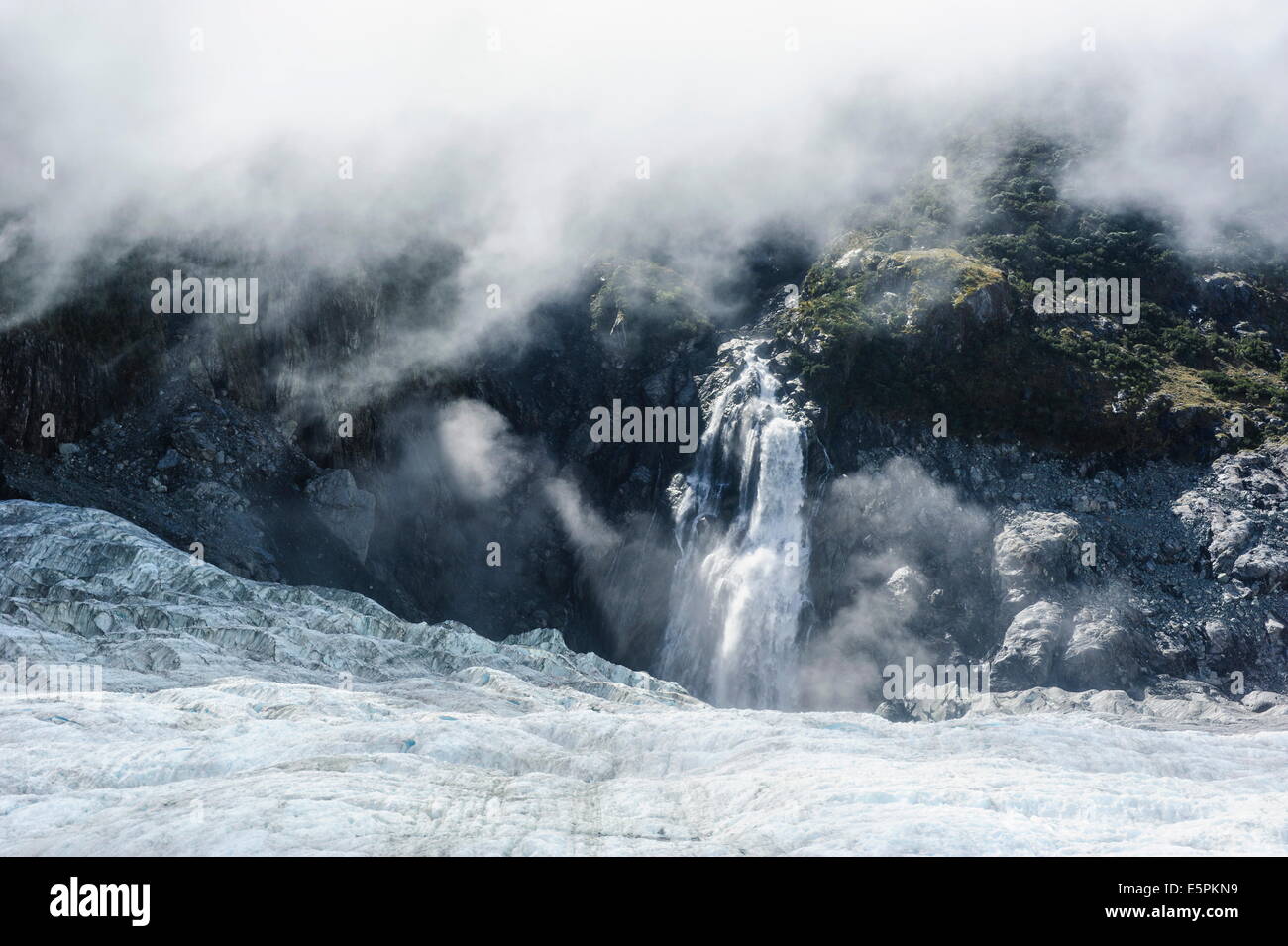 Antena de una cascada que desemboca en el hielo del glaciar Fox, Westland Tai Poutini National Park, Isla del Sur, Nueva Zelanda Foto de stock