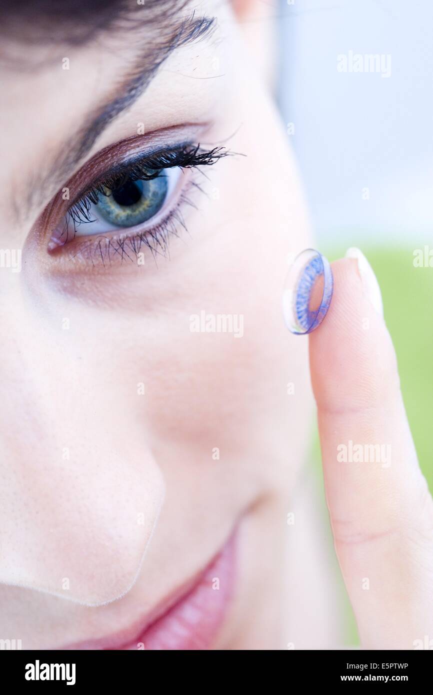 Mujer poniendo una lente de contacto de color en su ojo. Foto de stock