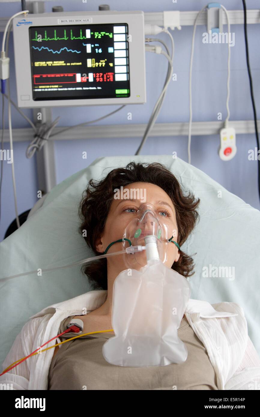 Paciente con mascarilla de oxígeno para asistencia respiratoria en urgencias. Foto de stock