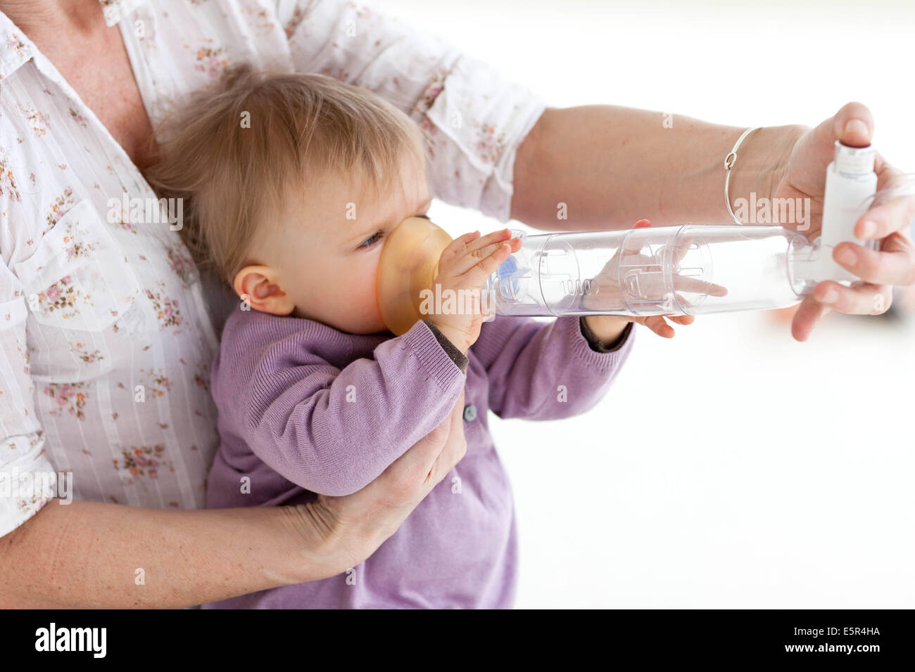 Madre dándole 13-month-old baby girl bronchodilatator con un espaciador (la  cámara de inhalación) para el tratamiento del asma Fotografía de stock -  Alamy
