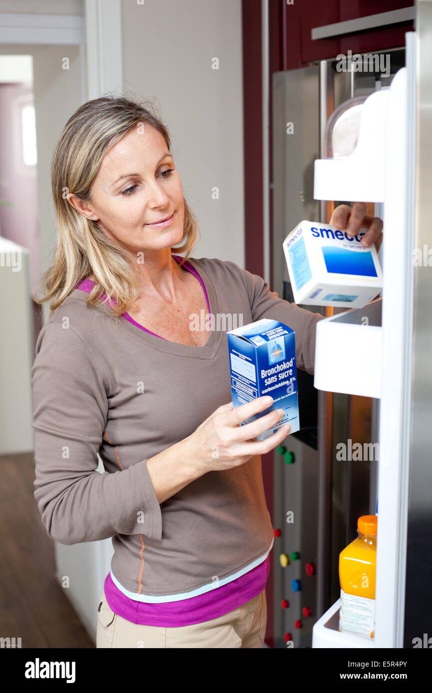 Mujer poniendo medicamentos dentro de un refrigerador. Foto de stock