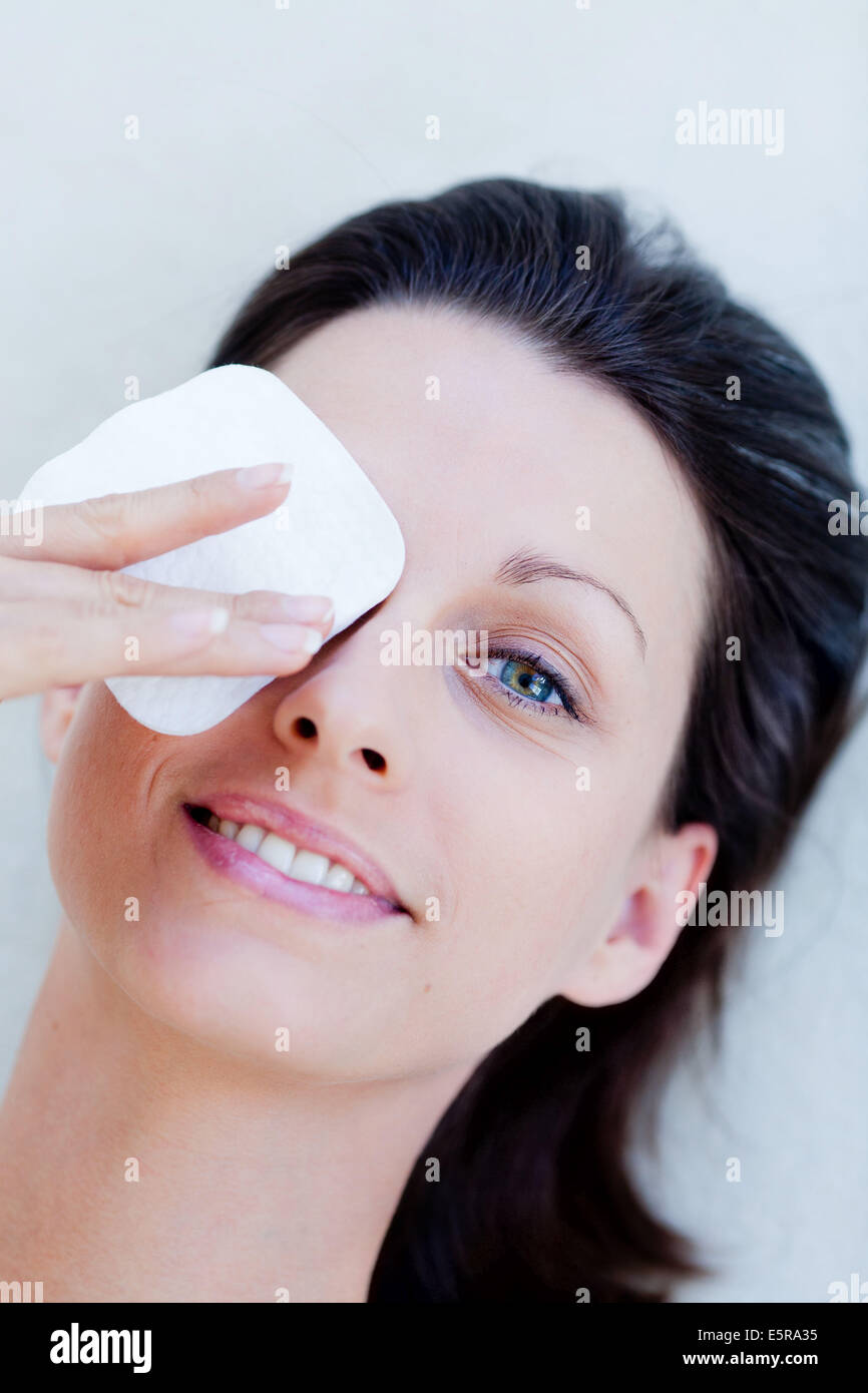 Mujer aplicando una gasa comprimir en su ojo. Foto de stock