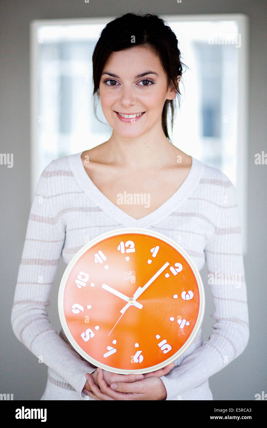 Mujer sosteniendo el reloj anaranjado. Foto de stock