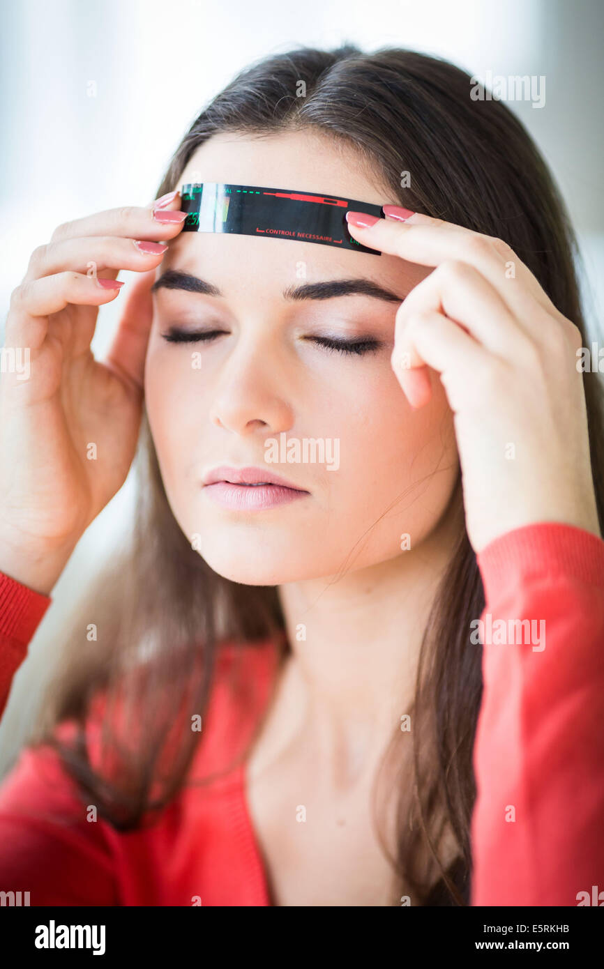 Mujer controlar su temperatura con un termómetro de tira Fotografía de  stock - Alamy