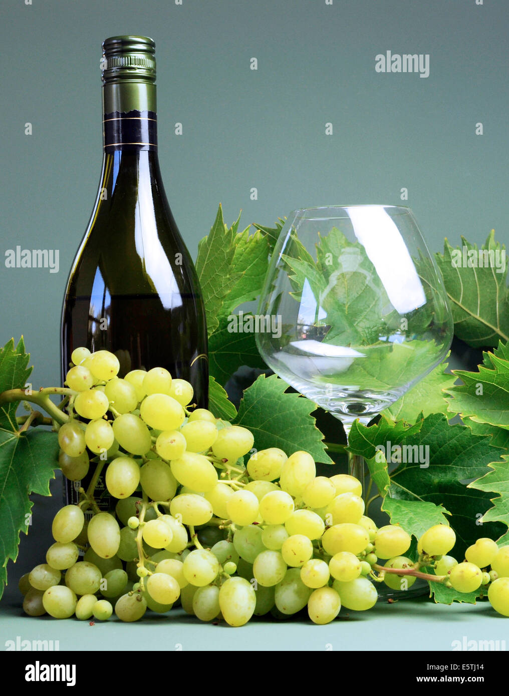 Botella de vino blanco, el vaso de vino con un gran montón de sultana uvas y hojas de vid de uva. Foto de stock