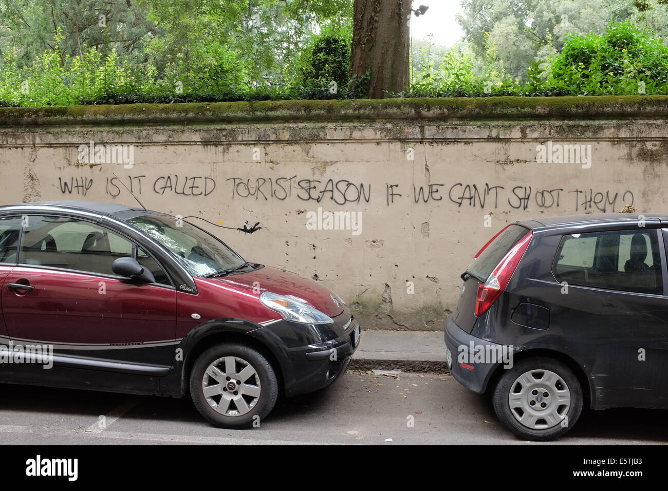 Graffiti alegre reza: "Por qué se llama temporada turística si no podemos disparar contra ellos?". Foto de stock