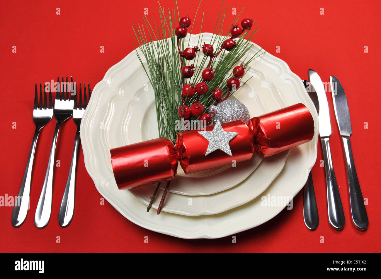 Moderno y luminoso rojo para poner la mesa de Navidad con cracker y  chucherías, platos y cubiertos, sobre un mantel rojo de fondo Fotografía de  stock - Alamy