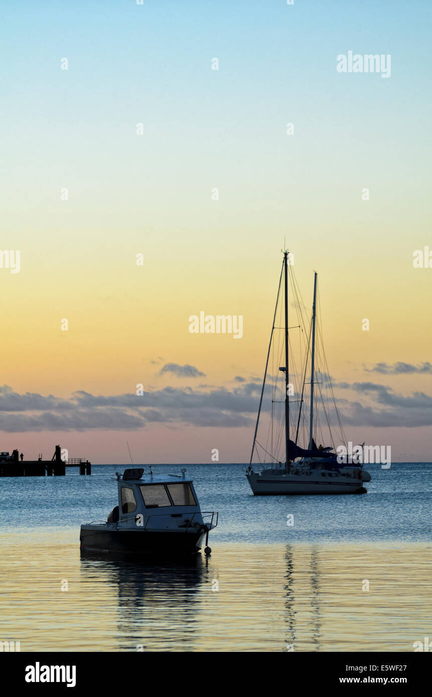 Escena tranquila - Barcos en reposo cerca del atardecer en un tranquilo puerto tropical. Foto de stock