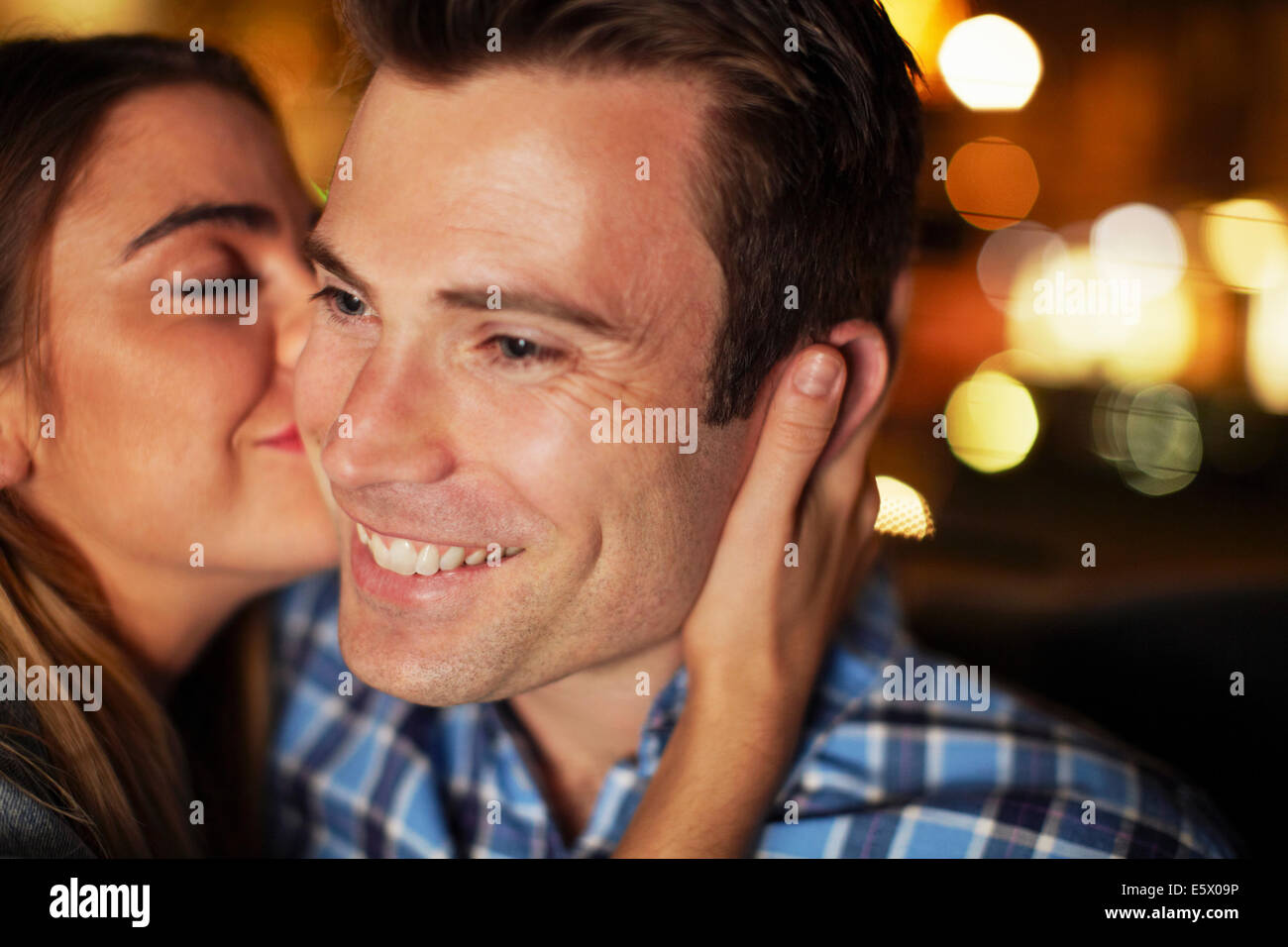 Pareja compartiendo beso en la mejilla en taxi de la ciudad en la noche Foto de stock