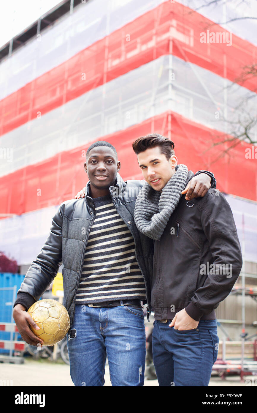 Retrato de dos jóvenes en la calle sosteniendo un balón de fútbol Foto de stock