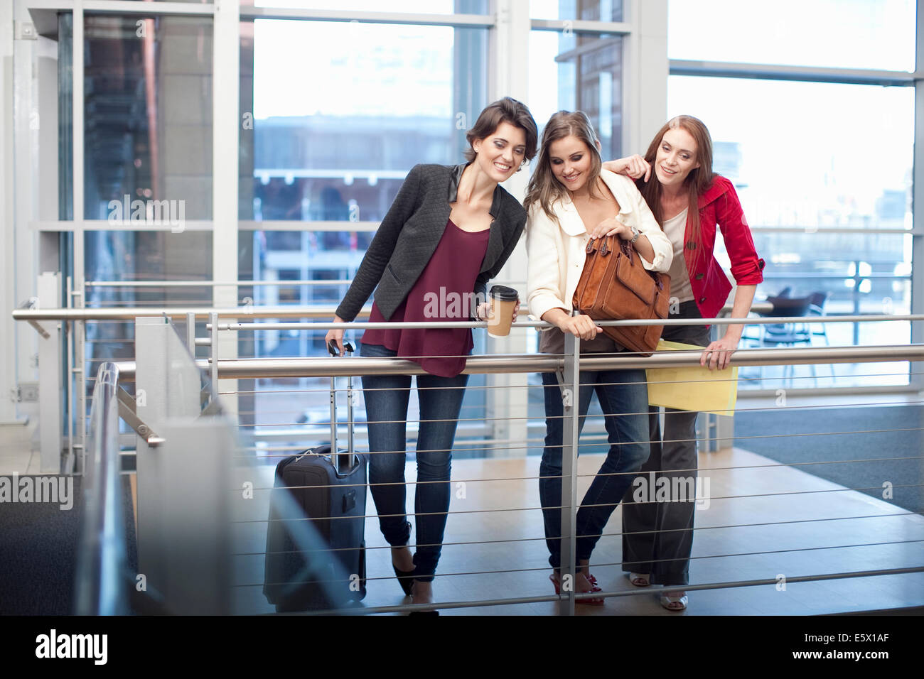 Tres mujeres empresarias viendo desde el balcón en el centro de conferencias Foto de stock