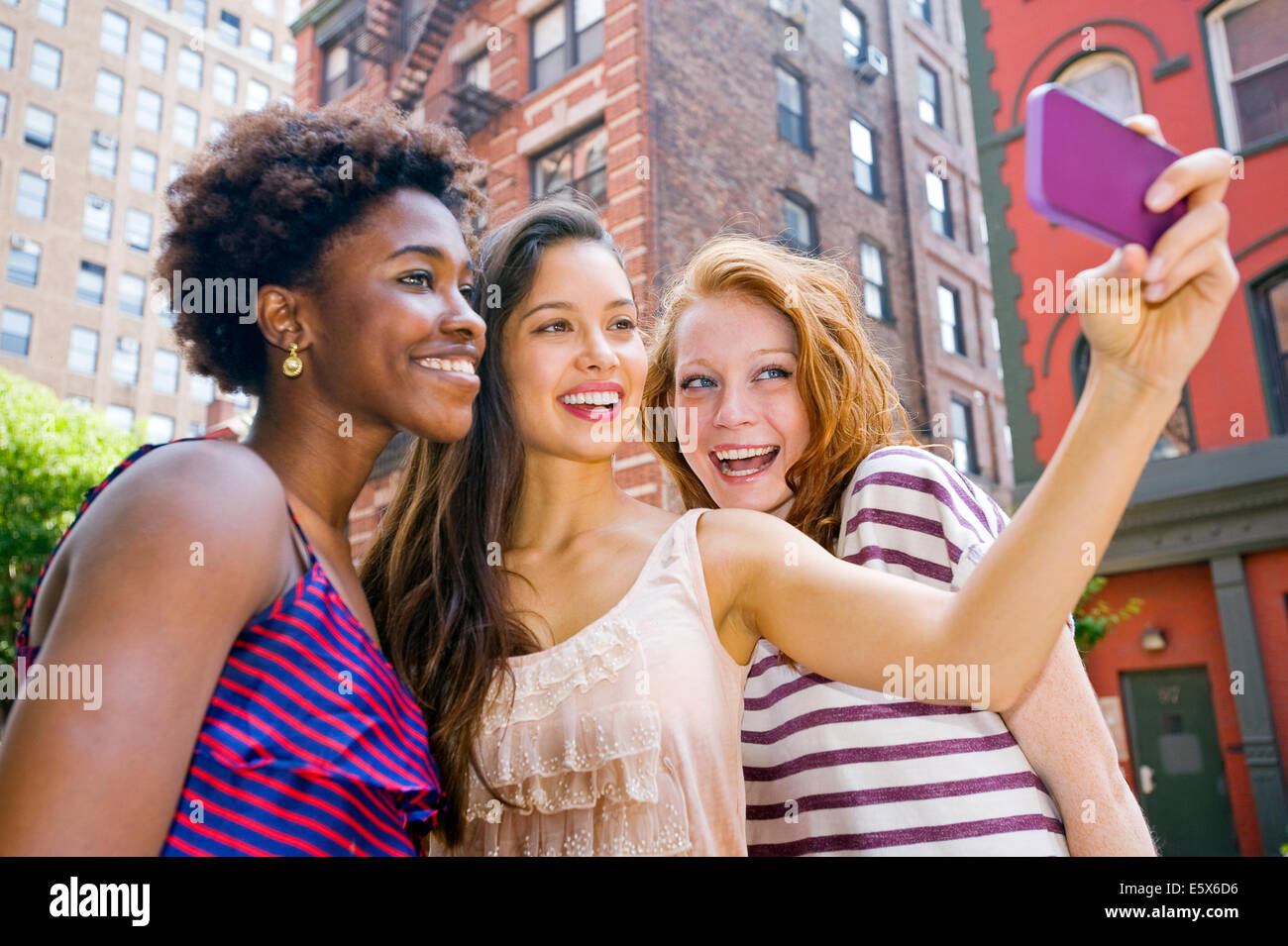 Tres jóvenes mujeres que toman la imagen de sí mismos a través de teléfono móvil Foto de stock