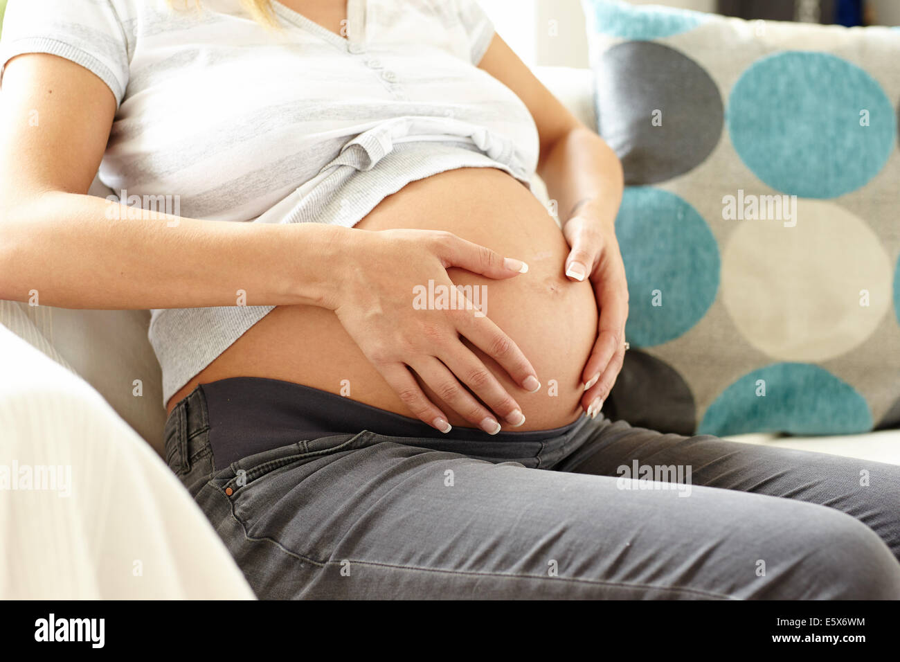 La mujer embarazada se sentó en el sofá relajante Foto de stock