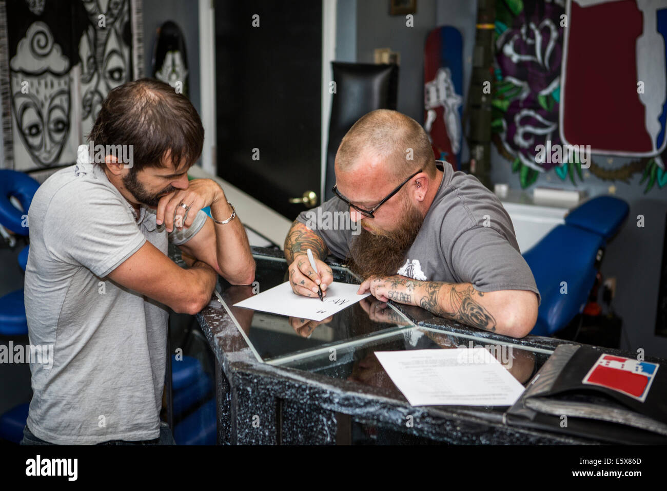 Dibujo del artista de tatuaje ideas con un cliente. Foto de stock