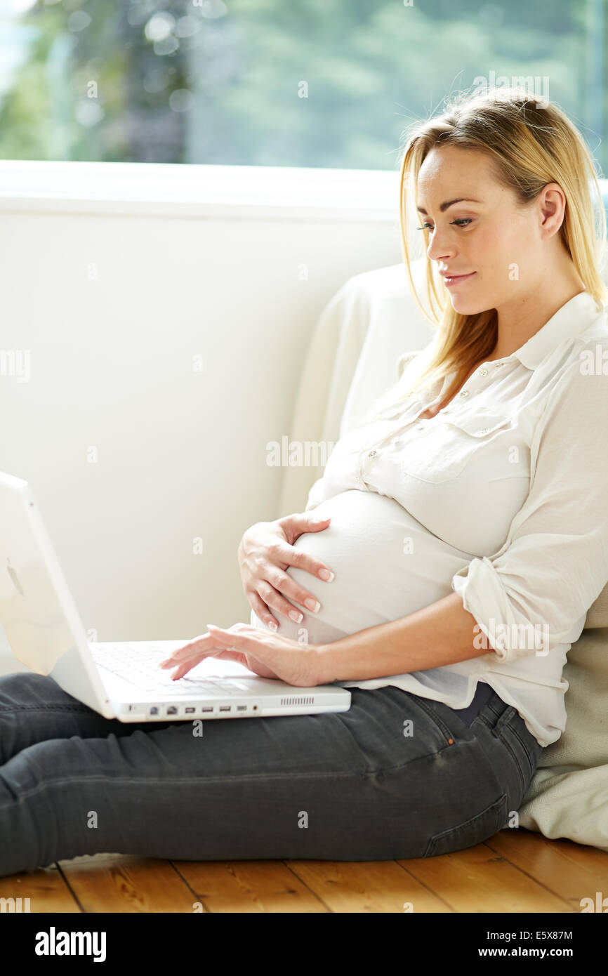 Embarazada utilizando equipo portátil Foto de stock