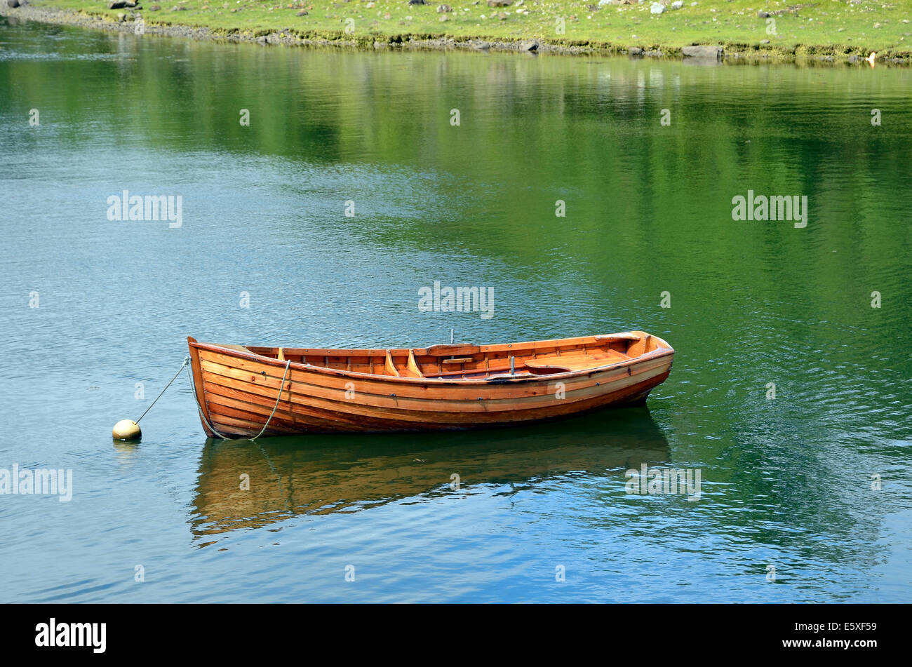 Un pequeño bote a remo de madera construidas de clinker atado a una boya de amarre en el puerto de Westport Quay, Mayo, Irlanda. Foto de stock
