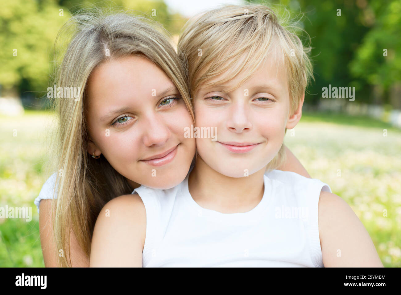 Hermosa niña rubia de 12-13 años en ropa informal posando en la calle.  Concepto de estilo de vida infantil. Crear espacio de copia. Mantenga  pulsado el botón azul s Fotografía de stock 