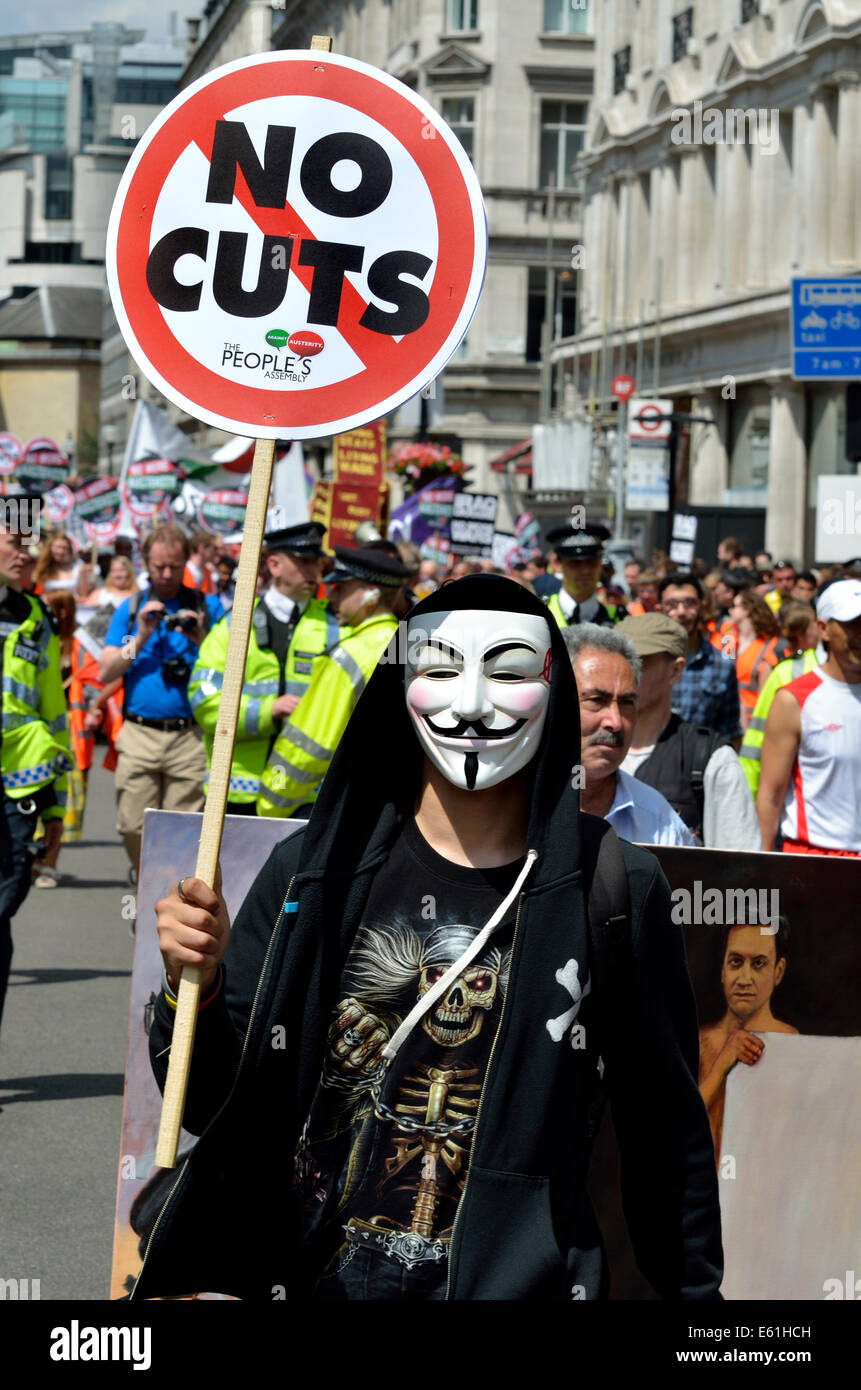 Manifestante en V de máscara con "sin cortes" pancarta a anti-austeridad por Londres, marzo de 2014. Kaya Mar (caricaturista político) detrás Foto de stock