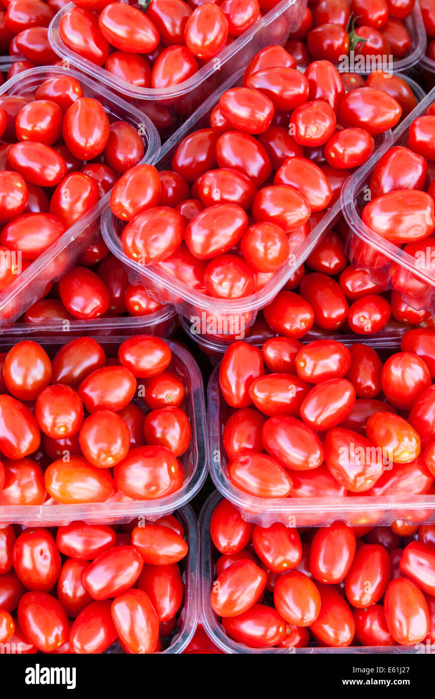 Close-up de tomates en bandejas de plástico apilados para su venta en un puesto en el mercado. Foto de stock