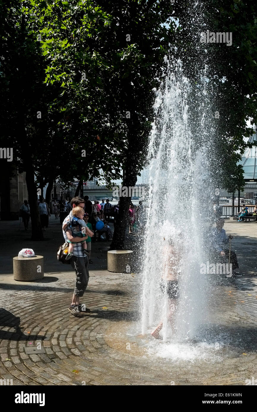 Un joven se enfría del calor por pie dentro de una fuente de agua en Londres del Banco del Sur. Foto de stock