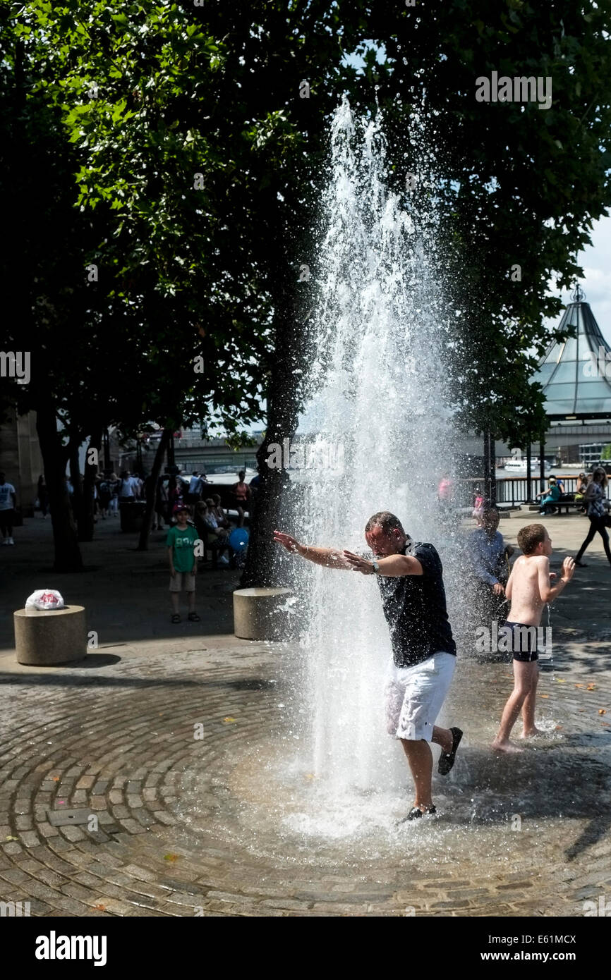 Un hombre va a una fuente de agua para escapar del calor en Londres. Foto de stock